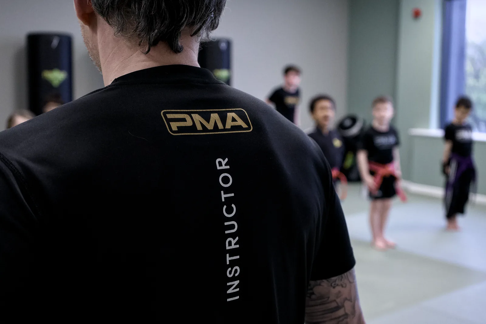 An instructor in a PMA INSTRUCTOR shirt facing a class