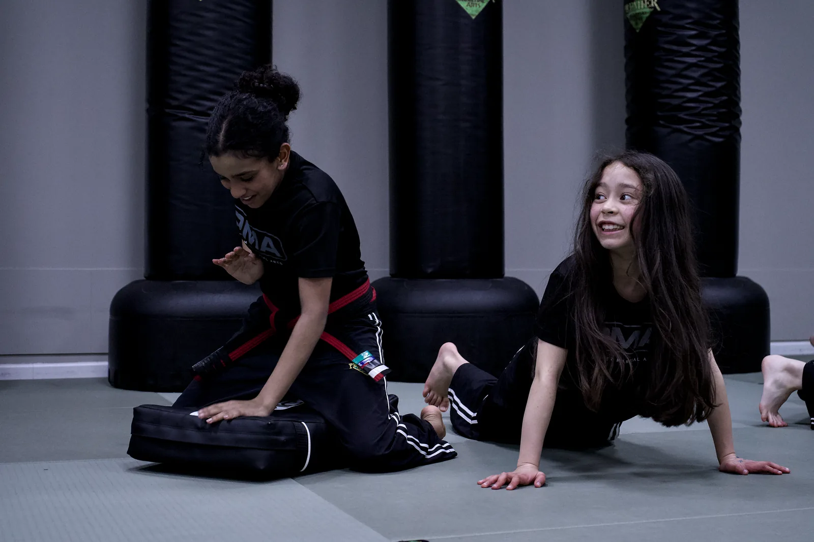 Two girls on the mat during a drill, one smiling across at her partner