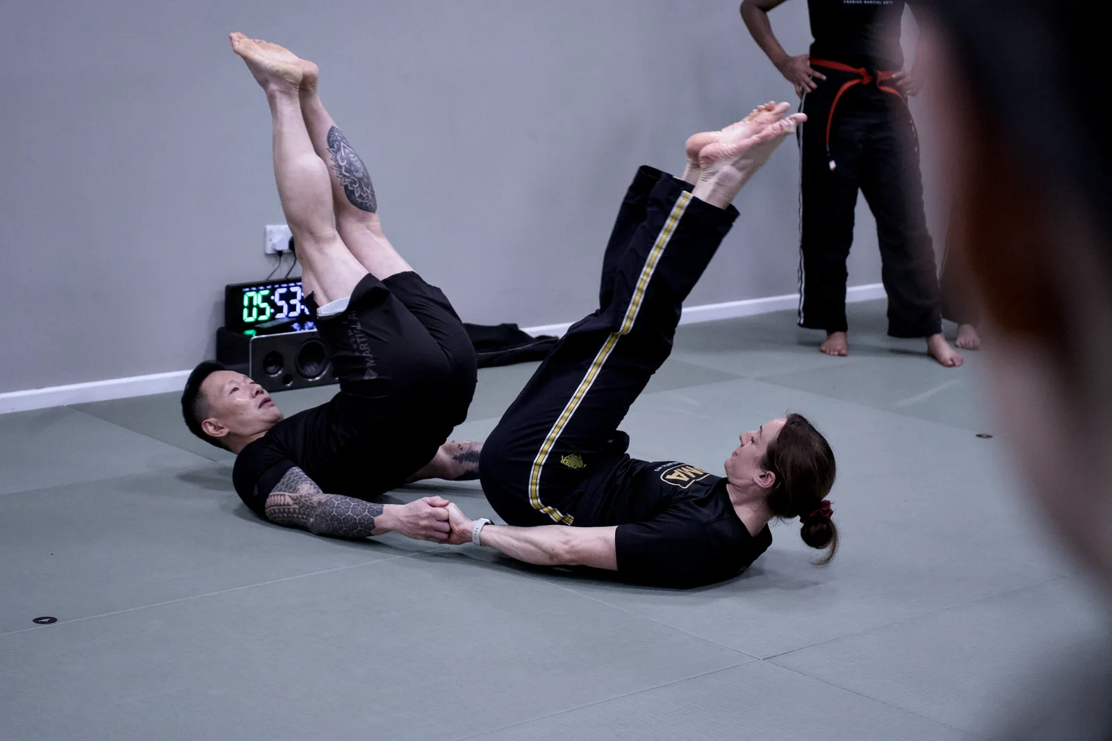 Two adults doing leg raises side by side on the mat